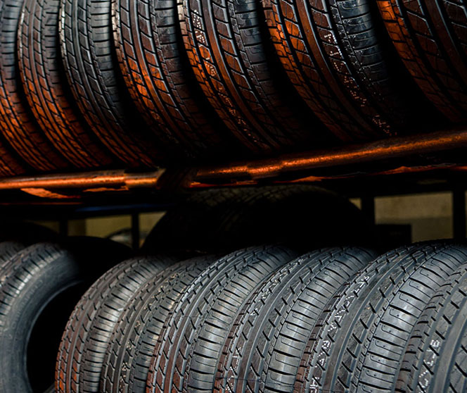 Stacks of new car tires arranged on metal racks in a tire shop